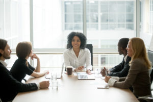 Woman sitting at the head of a boardroom table.